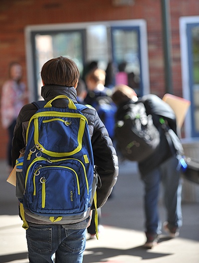 Student walking into school Photo: Student with backpack walking into Jason Lee Middle School